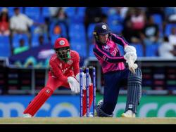 Scotland’s Brandon McMullen plays a shot as Oman wicketkeeper Pratik Athavale looks on during an ICC Men’s T20 World Cup cricket match at the Sir Vivian Richards Stadium in North Sound, Antigua and Barbuda, yesterday.