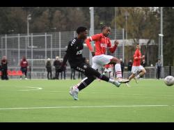 Kingston Football Academy under-15 captain Jaeden Morgan (left) strikes the ball ahead of a PSV Eindhoven player during the club’s tour of the Netherlands in April. 