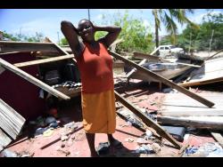 Natalee Bartley, a resident of Portland Cottage, Clarendon, looks at the remains of her home which was destroyed during the passage of Hurricane Beryl.