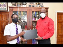 File photo shows Leighton McKnight (right) presenting one of two laptops donated by PwC Jamaica to Kingston College student Andrew Campbell during the David ‘Wagga’ Hunt Foundation presentation ceremony in 2022.