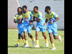 Penwood High School players embrace Jason Keyes (second left) after he scored against Kingston College during their drawn ISSA/WATA Manning Cup football match at Maverley playing field yesterday. The game ended 2-2.