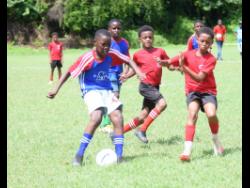 Granville Primary and Infant School’s Kahwaja Ladrick (left) competes with Montego Bay Prep’s Rajon Shaw and Cooper Dwyer (right) during the Junior Cup Under-11 Football Competition at Cornwall College on Saturday.