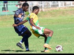 Kivann Salmon (right) of Excelsior High shields the ball from Donald Stewart of Jamaica College during yesterday’s  Manning Cup match at  Excelsior High. Jamaica College won 3-1.