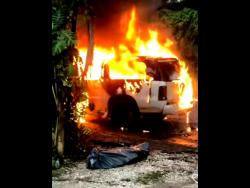 Credit: Screen grab taken from dutty_johnkrow_official_page Screen grab shows the burning hearse with the body laying covered close by.