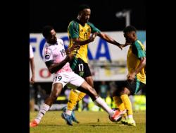 Jamaica’s Jashaun Anglin (centre) and Christopher Ainsworth (right) tussle for the ball with Trinidad and Tobago’s Noah Powder during their friendly international football match at the Anthony Spaulding Sports Complex last night. The match ended 1-1.