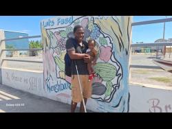  Dwayne Walker makes his way home, cane in one hand and his 11-month-old son in the other.