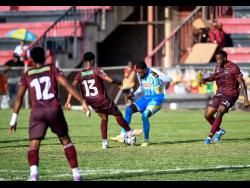 Credit: Matthew McKoy Leonardo Jibbison of Waterhouse FC (second right) is surrounded by Chapelton Maroons players Deandre Cunningham (right), Dunsting Cohen and Andrew Vanzie(left) during the Jamaica Premier League football match at Anthony Spaulding Sports Complex yesterday. The game ended 1-1.