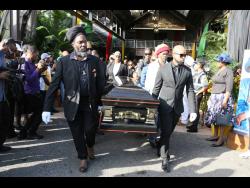 Pallbearers carry reggae legend Cocoa Tea from The Verandah, Clarendon Park, yesterday.