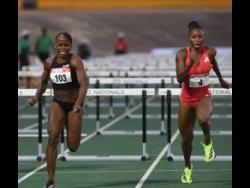 Megan Tapper (left) wins the women’s 100 metres hurdles final ahead of race favourite Ackera Nugent at the Puma JAAA National Junior and Senior Athletic Championships at the National Stadium on June 29.