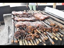 Jerk pork and sausage being cooked on pimento wood.