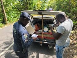 A member of the Area 2 Agricultural Protection Branch verifies documents from this farmer during a tour of farming communities in St Ann.