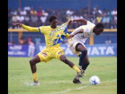 St Elizabeth Technical High’s Justin McPherson (left) and Munro College’s Chandon Roache battle for the ball during their Zone E football match in ISSA daCosta Cup at STETHS on Saturday. STETHS were on fire yesterday, slamming Sydney Pagon 17-0.
