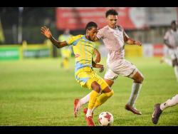 Shamarie Dallas (left) of Waterhouse runs with the ball while Dante Peralto of Chapelton Maroons reacts during the Jamaica Premier League football match at Drewsland Mini Stadium in Kingston last night. Waterhouse won 3-0.
