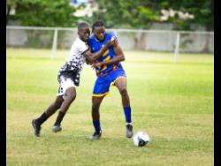 RJRGLEANER’s Kennario Henry (right) is fouled by a Jamaica Customs opponent as he looks to play the ball during the KSAFA Business House football preliminary round match against Jamaica Customs at Winchester Park, St. George’s College. RJR GLEANER will tackle defending champions NHT in tomorrow’s final at Ashenheim Stadium, Jamaica College.