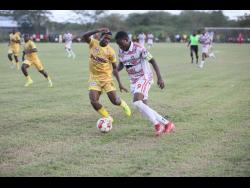 Credit: Nathaniel Stewart Glenmuir’s Orane Watson goes on a dribble while being chased by Garvey Maceo’s Ajani Johnson during their ISSA daCosta Cup football match at Garvey Maceo on Tuesday.