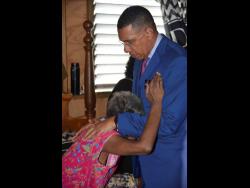 Prime Minister Dr Andrew Holness consoles the grandmother of Jushane Edwards as he visited the Commodore area of Linstead, St Catherine, yesterday, following a deadly shooting on Sunday.