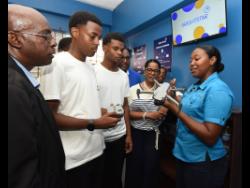Credit: Ian Allen Maria Timbawala (right), of the Mona Geoinformatics Institute, explains how to fly a drone to attendees during the opening of Brightstar Lottery’s 15th Digital Learning Centre and third annual Drone Technology Workshop at the Trench Town Community Development Centre on Tuesday.