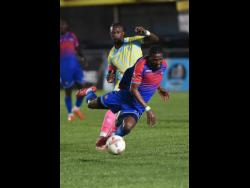 Nevaun Turner (front) of Dunbeholden FC is tripped by Revaldo Mitchell of Waterhouse FC during their Jamaica Premier League football match at Drewsland Mini Stadium on Sunday. The game ended 0-0.