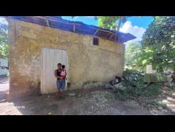 Credit: Almando Smith Natasha Sinclair stands outside her home with her youngest child in Kent Village, in the Bog Walk Gorge in St Catherine.