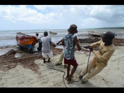Credit: Ian Allen Fishermen at Rocky Point, St Thomas, move their boat to higher ground in anticipation of Tropical Storm Melissa hitting the island.