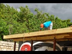 Credit: Matthew McKoy Mark Daley fixes his roof at Black Beard Pub on New Street in Port Royal on Thursday.