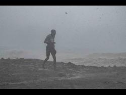 A man is seen running along the shoreline at Seven Miles, Bull Bay, St Andrew, as Hurricane Melissa slashed sections of the island yesterday.