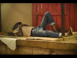 This man makes himself comfortable in Coronation Market in downtown Kingston yesterday as vendors say they are staying put despite the storm.