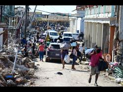 Persons make their way along Crane Road in Black River, St Elizabeth, carrying much-needed supplies.