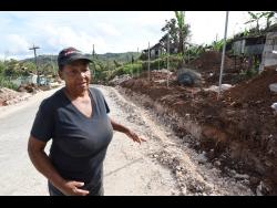 Cynthia Watt stands on the temporary detour cut through her yard in Lorrimers, Trelawny, after Hurricane Melissa.
