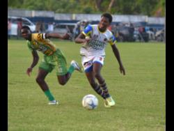 St. Elizabeth Technical High’s Kaieem Lewis (right) tries to outrun  Ocho Rios High’s Kawayne McInnis  during their  ISSA daCosta Cup round of 16 match at Drax Hall Sports Complex yesterday.