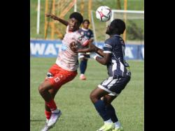 Sean Leighton (left) of Mona High School and Donald Stewart of Jamaica College compete for the ball during their ISSA WATA Manning Cup football match at Stadium East yesterday. The match ended 1-1.