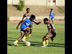 Shannon Power of Hydel High School (left) dribbles the ball as Isaiah Lee (right) of Charlie Smith High School reacts during the ISSA WATA Manning Cup football match at Stadium East on Saturday.