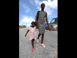 Credit: Ian Allen Photos Nadine Samuels walks hand-in-hand with her daughter, three-year-old Gabrielle Dixon, through the streets of Lewisville, St Elizabeth.