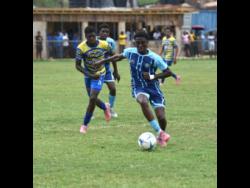 Credit: Ashley Anguin Manning’s School’s Jordan Turner (front) dribbles clear of Christiana High’s Darone Thomas during their Ben Francis KO quarterfinal match at Manchester High playing field yesterday.