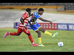 St Elizabeth Technical High School’s Kaieem Lewis shoots at goal while under pressure from Glenmuir High School’s Kamari Wray during the ISSA WATA daCosta Cup final at the National Stadium on Saturday.