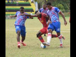 Montego Bay United’s Brian Brown (centre) is tackled by Portmore United’s Emelio Rousseau (left) and Tarick Ximines (right) during their Jamaica Premier League game at Jarrett Park in Montego Bay yesterday.