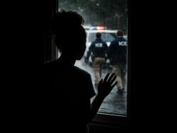 In this AI-generated image, Jane* stands at a window watching ICE agents outside, symbolising the fear and uncertainty faced by undocumented immigrants as court hearings approach and the threat of deportation looms.