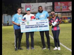 Jake Mahfood (left), commercial and  development manager of Wisynco, hands over an MPowa cheque for $2 million to Bruce Bicknell (second left), chairman of the Waterhouse FC, on Sunday at the Waterhouse Mini Stadium. Looking on are Chevon Lewis (second right), brand manager of MPowa at Wisynco and Aundreen Leslie, social media officer of Waterhouse. 
