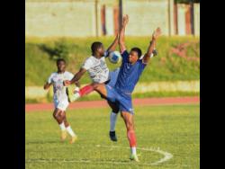 Jeovanni Laing (centre) of Cavalier FC and Andre Clennon (right) of Spanish Town Police FC challenge for the ball during the Jamaica Premier League football match at Stadium East on Monday. Cavalier won 5-0.