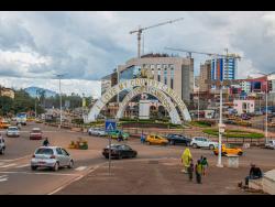 Cars drive through an intersection near a monument in Yaoundé, Cameroon.