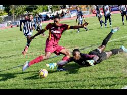 Daniel Russell, while representing Jamaica College (JC), dives at the feet of Wolmer’s Boys’ Deshawn Bernard to make a save during the ISSA Manning Cup football match at JC on Friday, September 27, 2019.