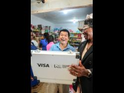 Danielle Cameron-Duncan (right), acting senior vice president for payments and channels at NCB, presents Zewei Zheng, owner of San San Haberdashery in St Ann’s Bay, with his $1 million second-place prize from the NCB Business Boost initiative. Zheng used the money to purchase food supplies for hurricane-affected families in his community.