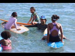 President of the Jamaica Surfing Association, Inilek Wilmot (second right), interacts with some of the children at the Next Wave JA surfing session in Bull Bay on Sunday. 