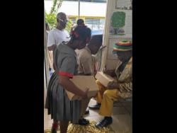 Eric Donaldson signs shoe boxes for students of Four Paths Primary School in Clarendon.