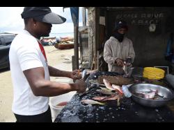 Vendors prepare fish for customers along Port Henderson Road, St Catherine.