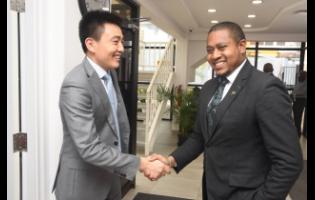 Huawei Jamaica CEO Bo Zhou (left) greets Floyd Green, minister without portfolio in the Office of the Prime Minister, at the tech company’s Kingston office last Thursday.