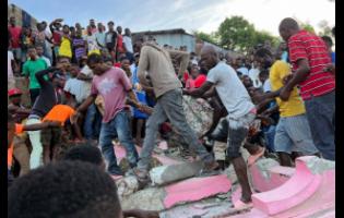 People carry an injured person away from a home that collapsed due to an earthquake in Jeremie, Haiti,  yesterday.