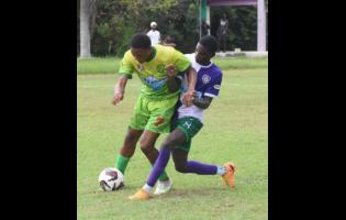 Ocho Rios High’s Joaquin Corothers (left) shields the ball from William Knibb Memorial High’s Theonjae Bennett during the ISSA/daCostaCup match at the William Knibb Sports Complex yesterday. Ocho Rios won 1-0.