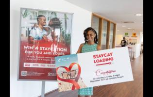 Simeca Alexander-Williamson poses with a symbolic voucher of her Luxury Staycation win courtesy of Digicel.