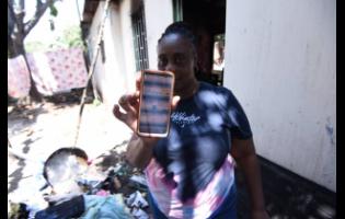 Trecia Ellis, the owner of the house where six firefighters were injured yesterday while putting out a blaze, shows her electricity bills on her smartphone.